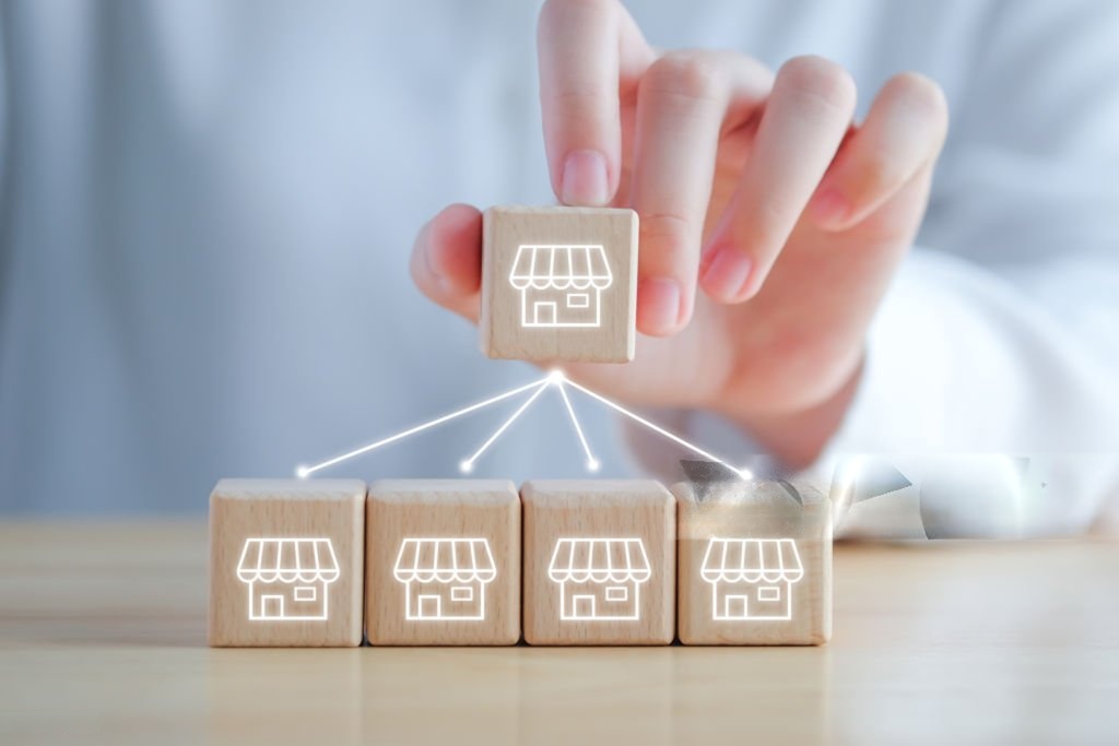Franchise growth concept with store icons on wooden blocks.