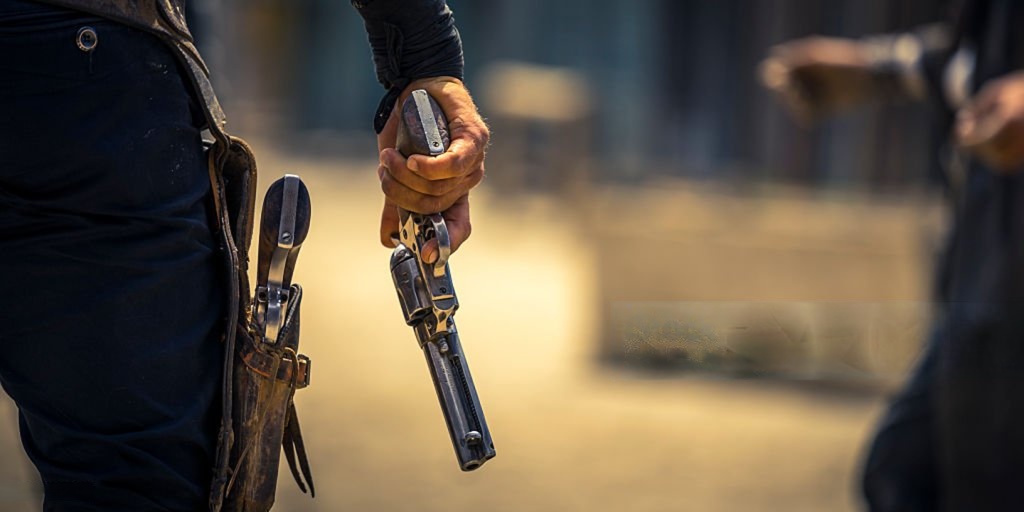 Feature image Person holding a revolver with a holstered gun in a Western-style setting