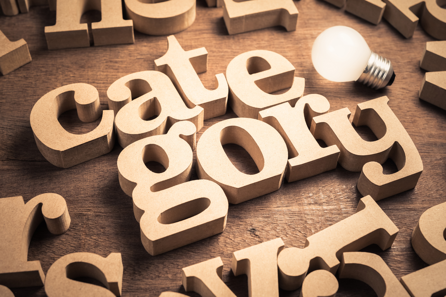 Wooden letters spelling “category” on a table with a light bulb.